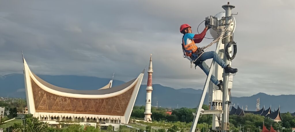 Teknisi jaringan XLSMART sedang melakukan pemeliharaan di atas menara BTS yang berada di Padang, Sumatera Barat. /Dok. Perseroan