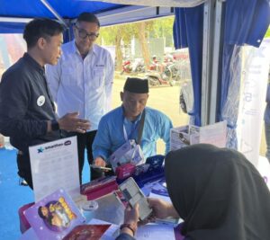 Head of Sales Regional Jabo-Jakarta XLSMART, Fedinan Oktavian (tengah), bersamaPetugas layanan pelanggan XLSMART melayani salah satu jamaah haji di Posko XLSMART Asrama Haji Bekasi, Jawa Barat, Rabu (22/4/2026). Paket haji XLSMART hadirkan konektivitas stabil, kuota besar, dan harga kompetitif bagi jemaah Indonesia. /XLSMART